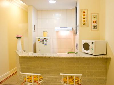 a kitchen with a microwave on a counter with two stools at Apartamento Ouro Negro in Rio de Janeiro