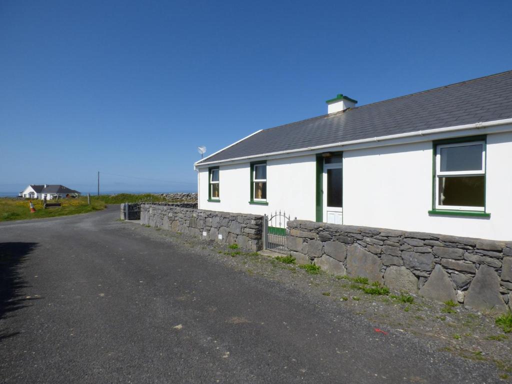 een wit huis met een stenen muur naast een weg bij Seaview Cottage in Ballyvaughan