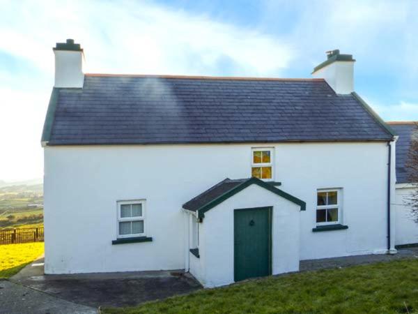 a small white house with a green door at Sugarbush in Eyeries