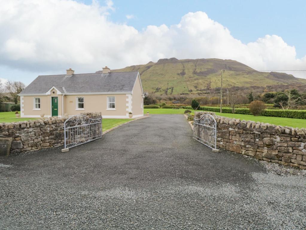 a house with a stone wall and a driveway at Tieve Baun in Ballaghnatrillick