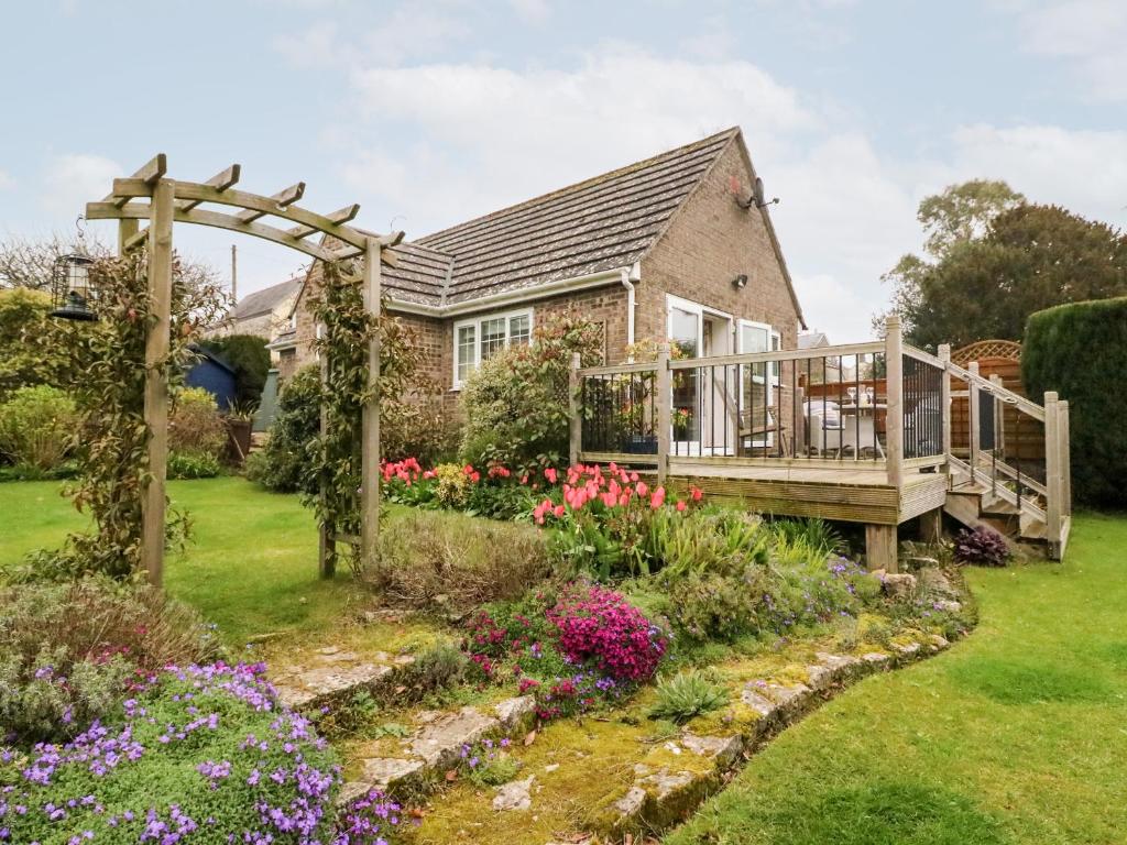 a house with a deck and flowers in the yard at Little Retreat in Upwey