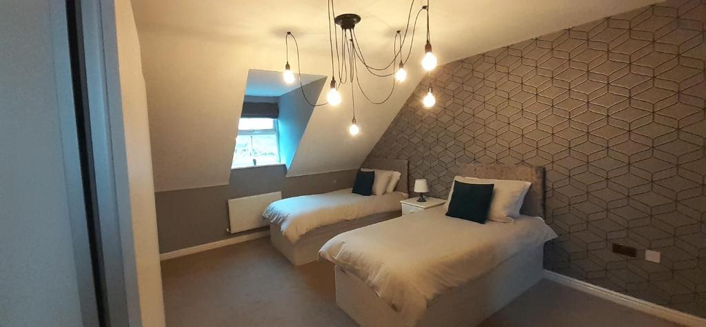 a bedroom with two beds and a chandelier at Hawksworth House, Birmingham Near NEC, HS2, Jaguar Land Rover, Bear Grylls Centre, Resorts World and Birmingham airport with a garage and free allocated parking in Kingshurst