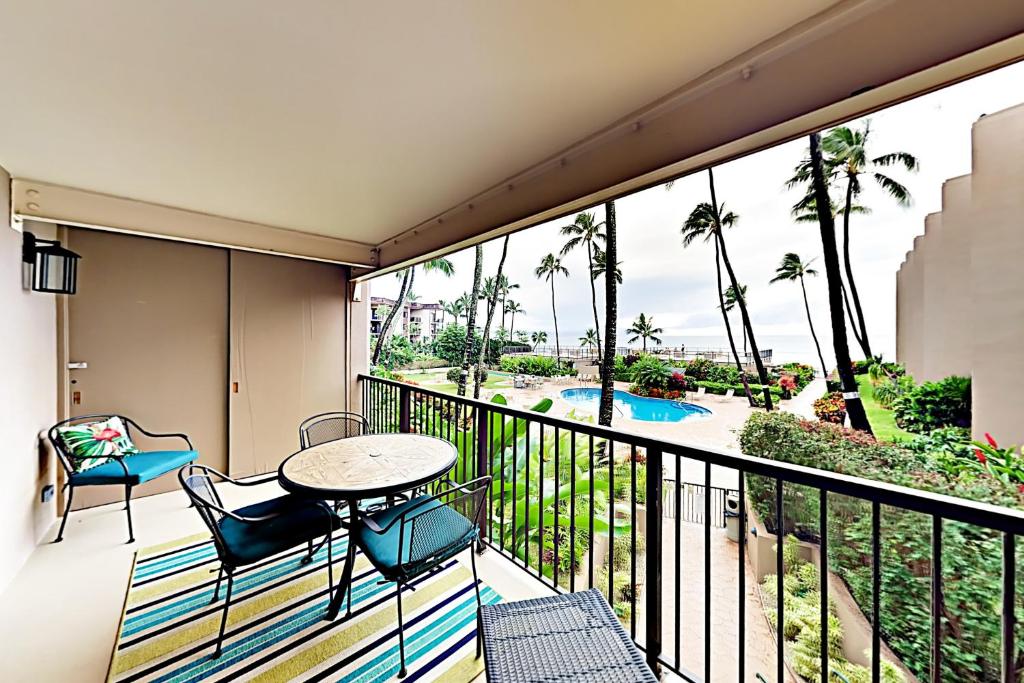a balcony with a table and chairs and a view of a pool at Hale Ono Loa 210 in Kahana