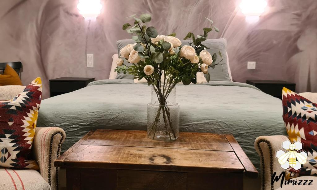 a vase of flowers on a table next to a bed at Le Mimizzz in Entraygues-sur-Truyère
