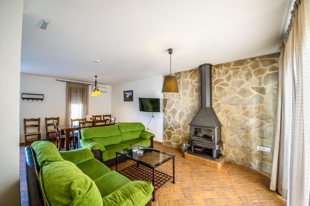 a living room with green couches and a fireplace at Apartamentos La Venta del Charco in Cardeña