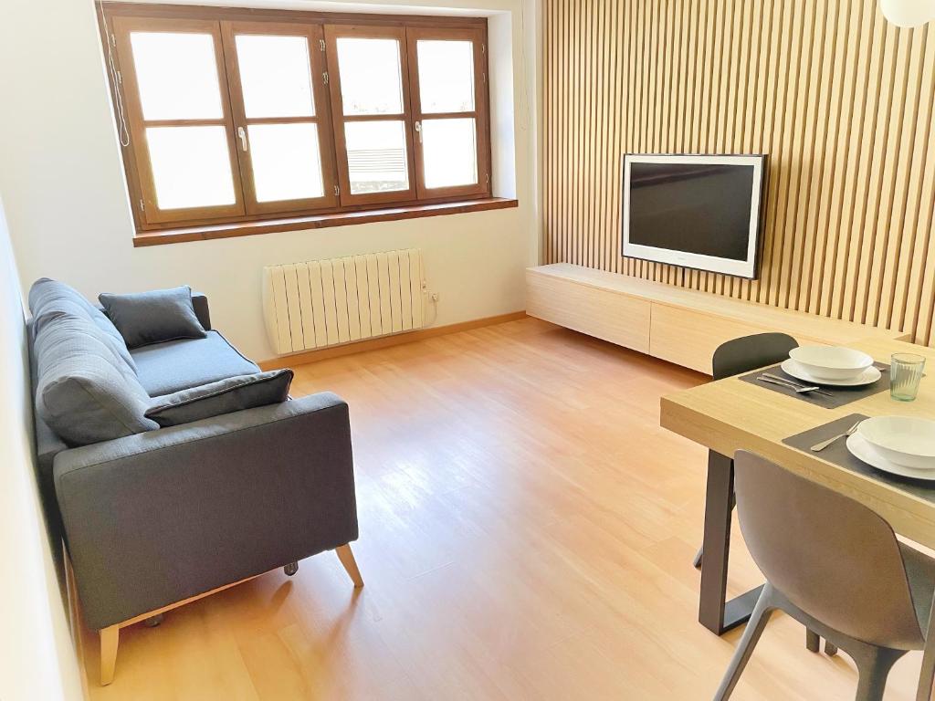 un soggiorno con tavolo, divano e TV di Apartamento Valle de Alba a Benasque
