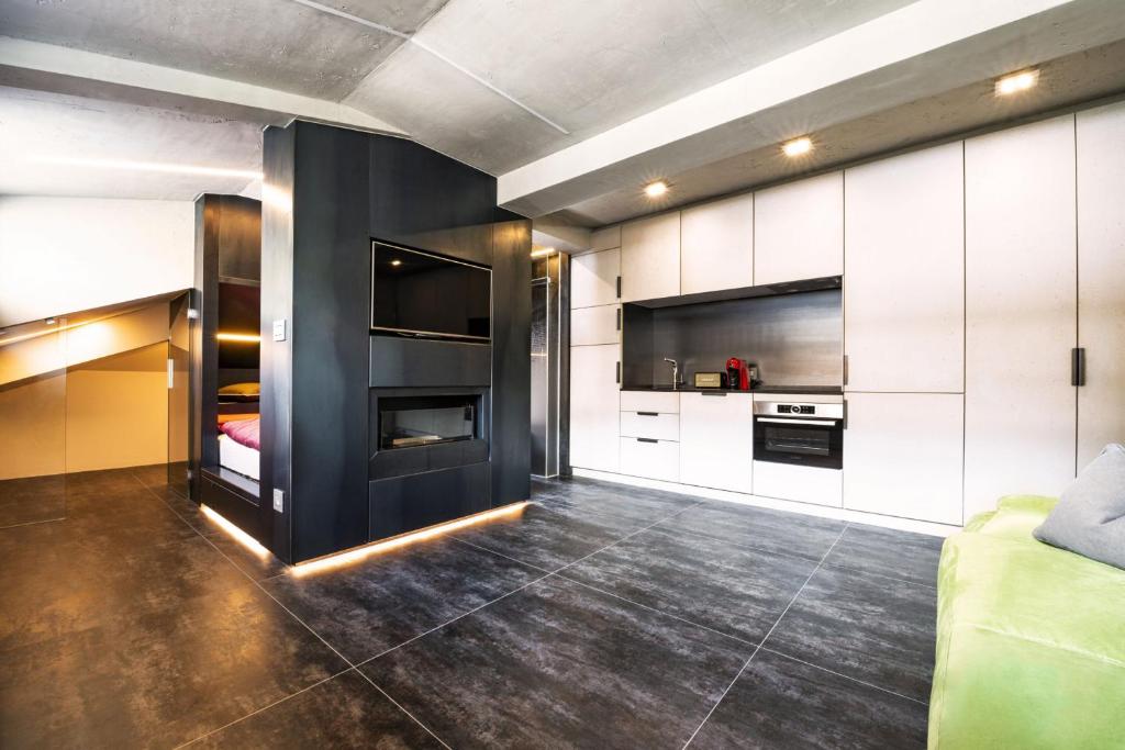 a kitchen with white cabinets and a black wall at Loft on 1236 in Ortisei