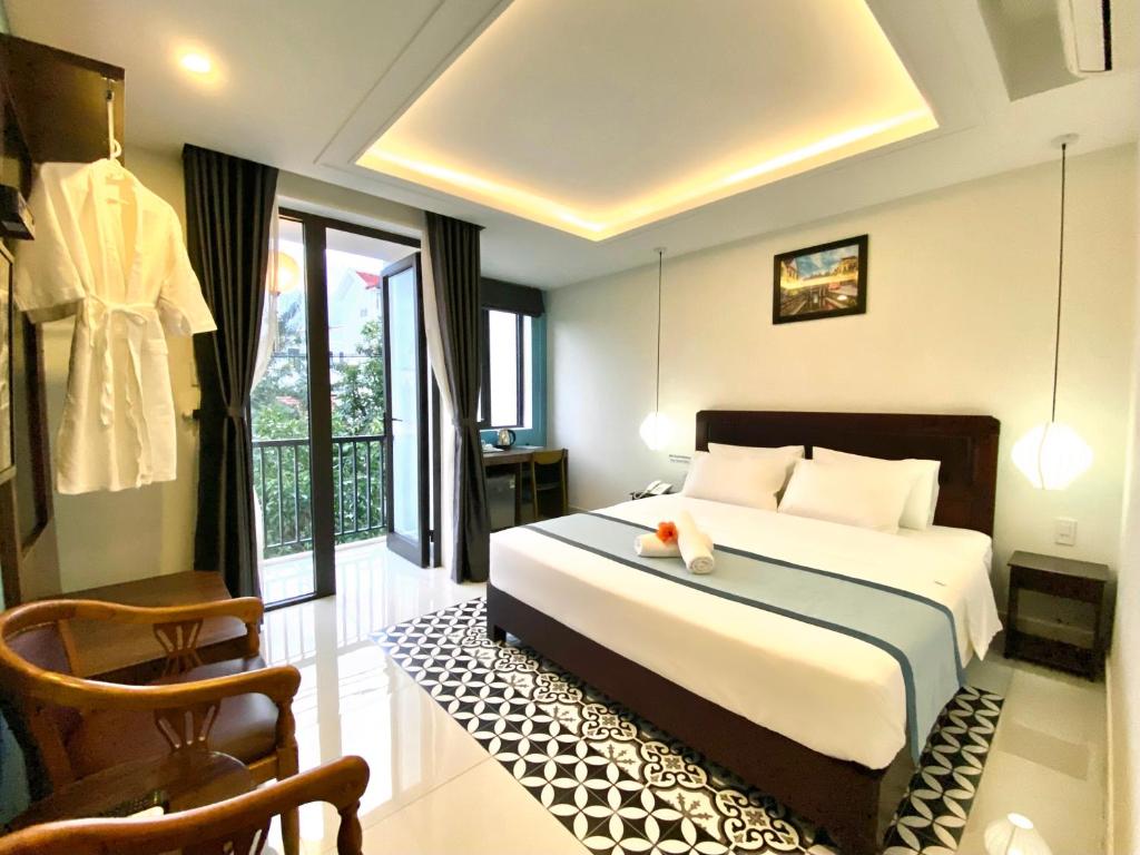 een slaapkamer met een bed en een stoel in een kamer bij Grand Holiday Hoian Villa in Hội An