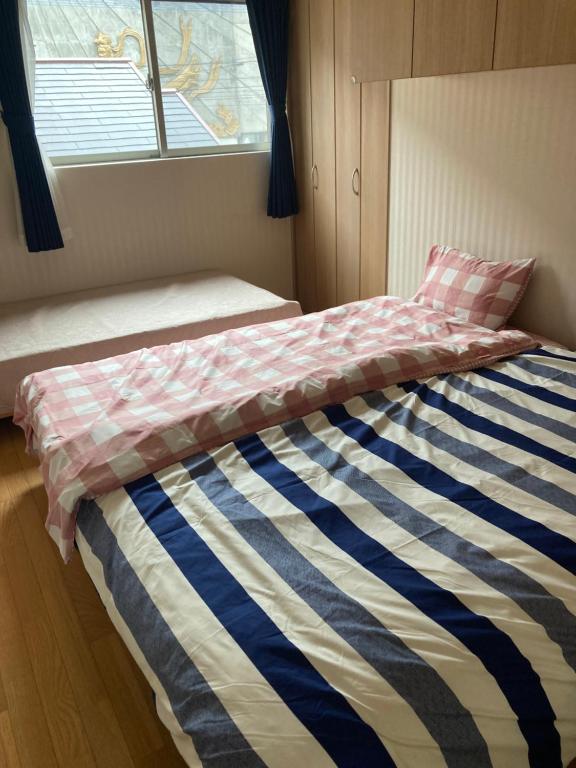 Un dormitorio con una cama con una manta a rayas. en 森のカフェ, en Beppu