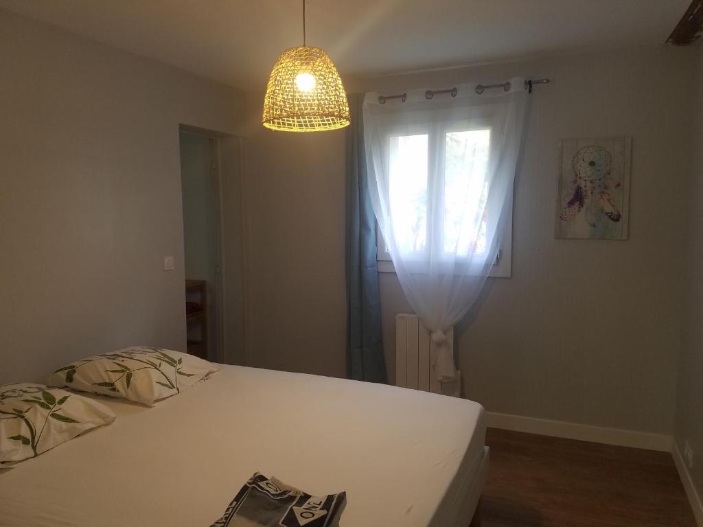 1 dormitorio con cama blanca y ventana en Gite Matilon, 5 min Eugénie les Bains, en Buanes