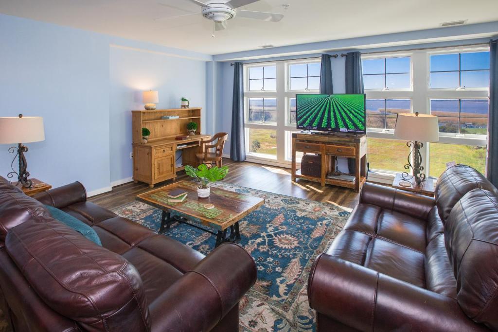 a living room with a leather couch and a television at The Sanctuary - Sunset Haven B335 in Virginia Beach