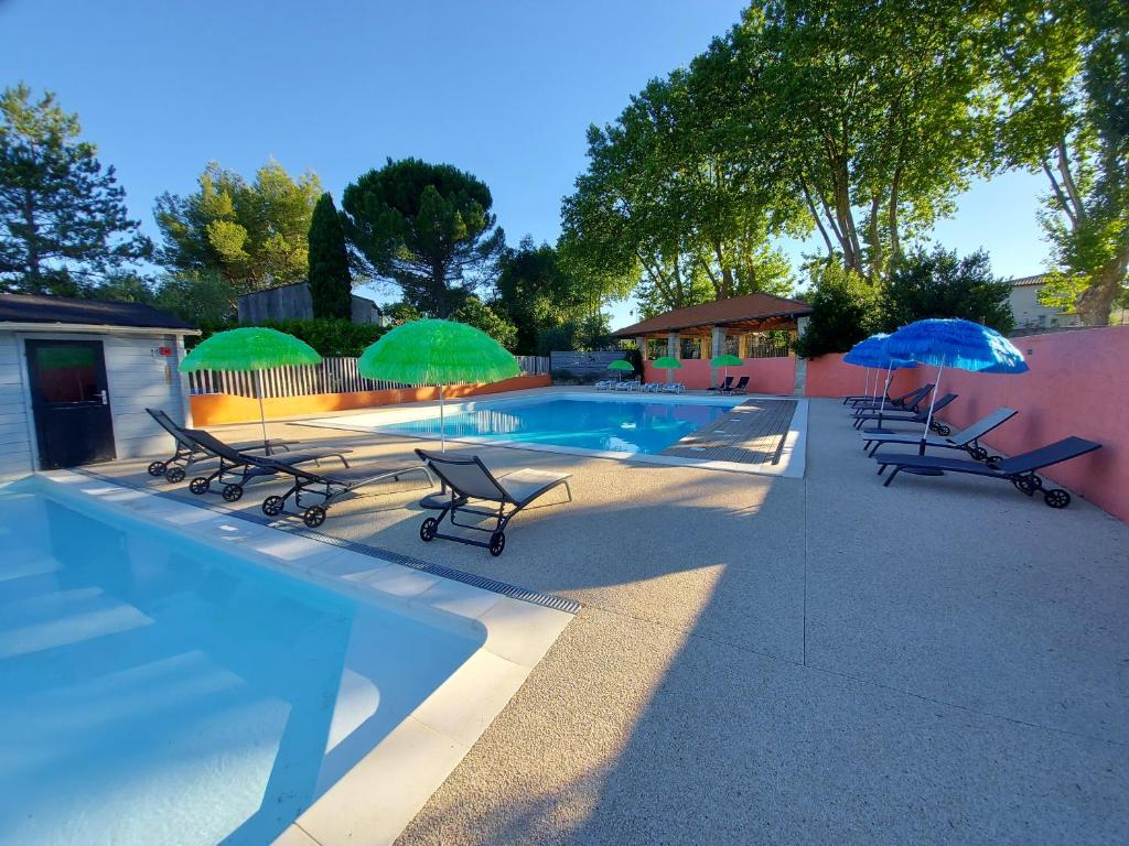 a swimming pool with lounge chairs and umbrellas at Camping Le Pre Saint-Andre in Souvignargues
