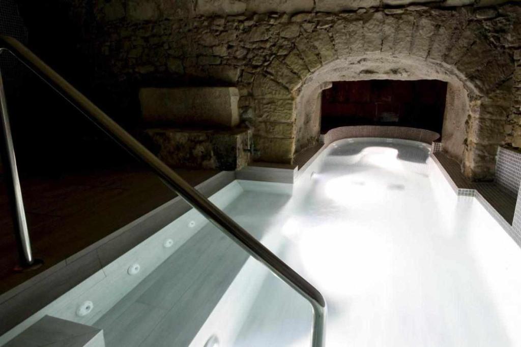 bañera en una habitación con pared de piedra en Cal Miqueló Puiggròs, en Puiggròs
