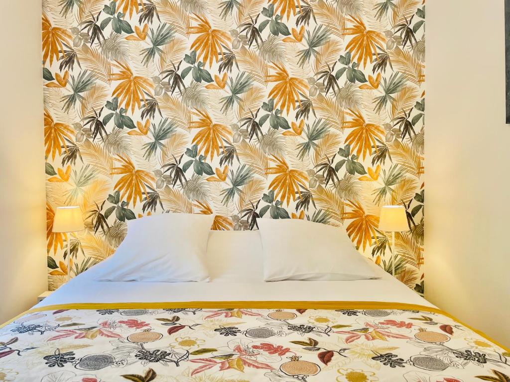 a bedroom with a bed with a floral wallpaper at Hotel De Ma Tante in Lamalou-les-Bains