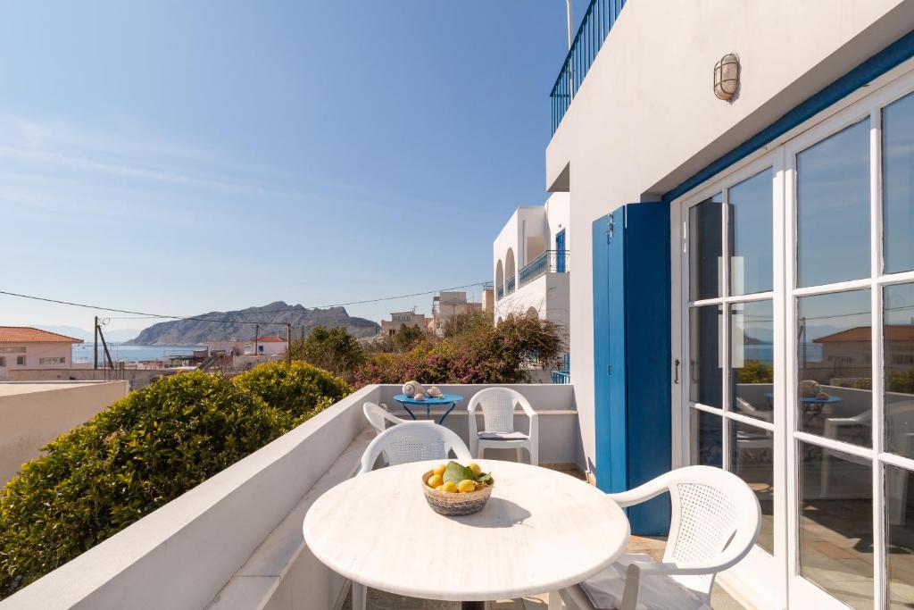 een tafel en stoelen op een balkon met uitzicht op de oceaan bij Aeginia Complex in Perdhika