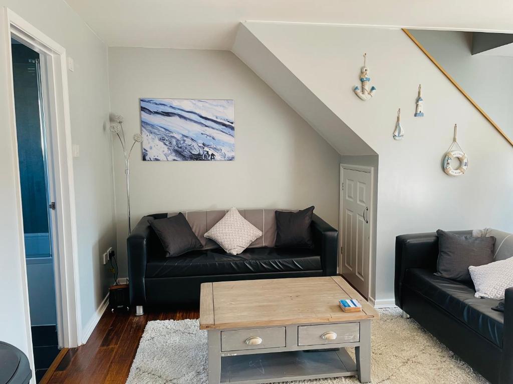 a living room with a black couch and a table at The Beach House, Suffolk Coast in Lowestoft