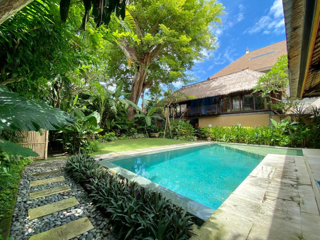 a swimming pool in front of a house at Little Tree House in Sanur