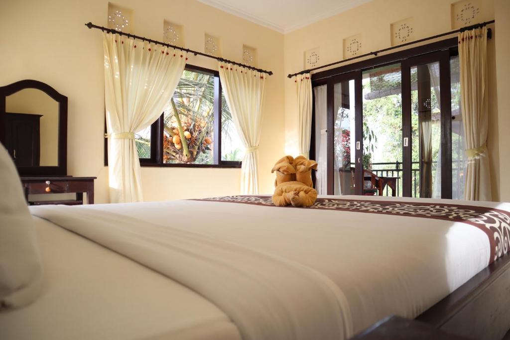 a teddy bear sitting on a bed in a bedroom at Wijaya Guest House Ubud in Ubud