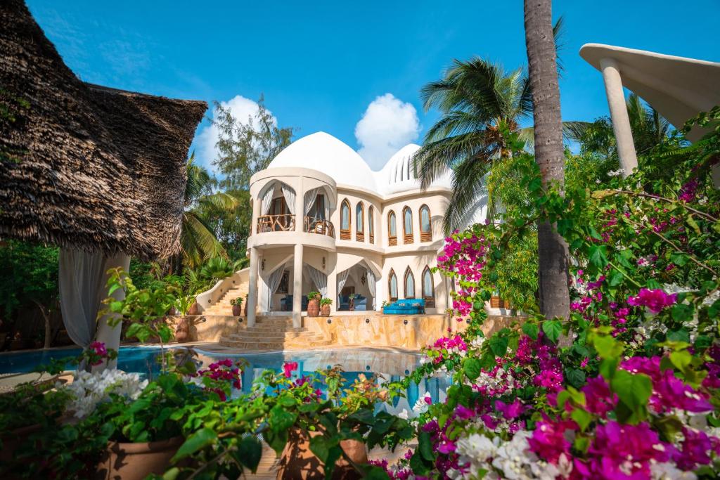 a villa with flowers in front of a swimming pool at Xanadu Luxury Villas & Retreat Zanzibar in Bwejuu