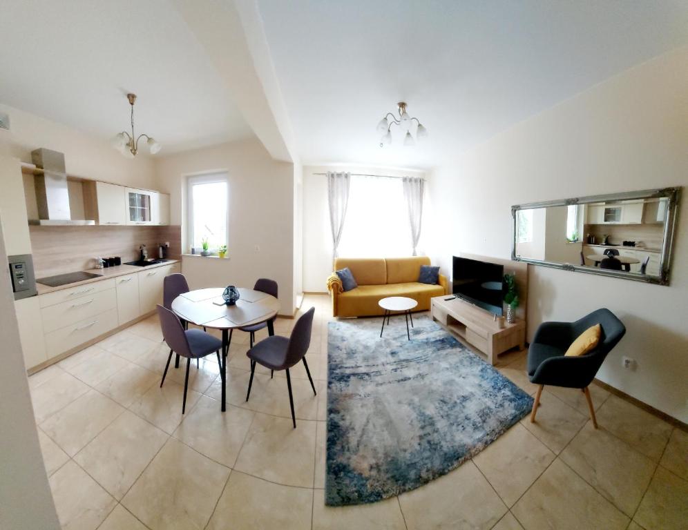 a kitchen and a living room with a table and chairs at Modlinska Apartments in Nowy Dwór Mazowiecki