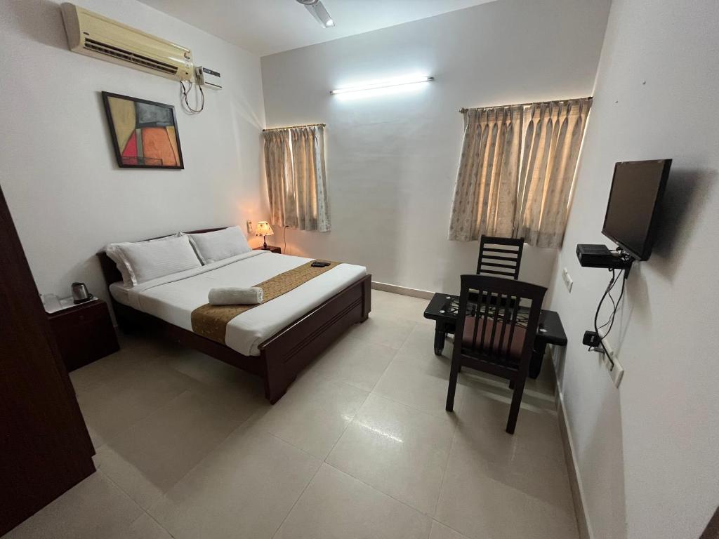 a bedroom with a bed and a chair and a television at Avuraa Hospitality India in Chennai