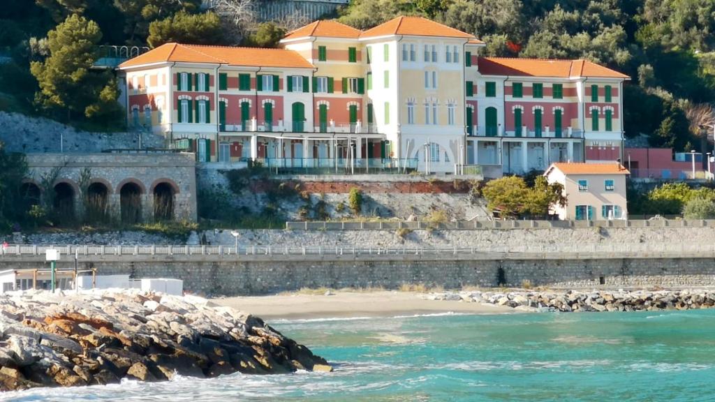 un grand bâtiment sur une colline à côté de l'eau dans l'établissement HOTEL DEL GOLFO, à Finale Ligure