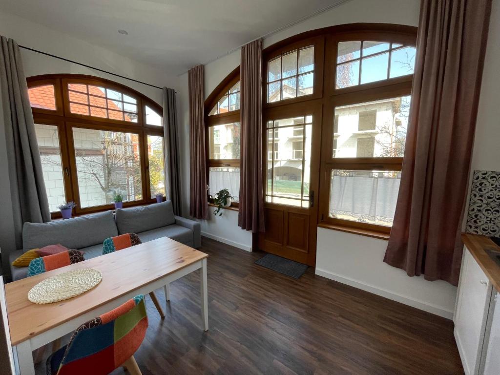 a living room with a table and some windows at Apartamenty Żeromskiego 8 in Ustka