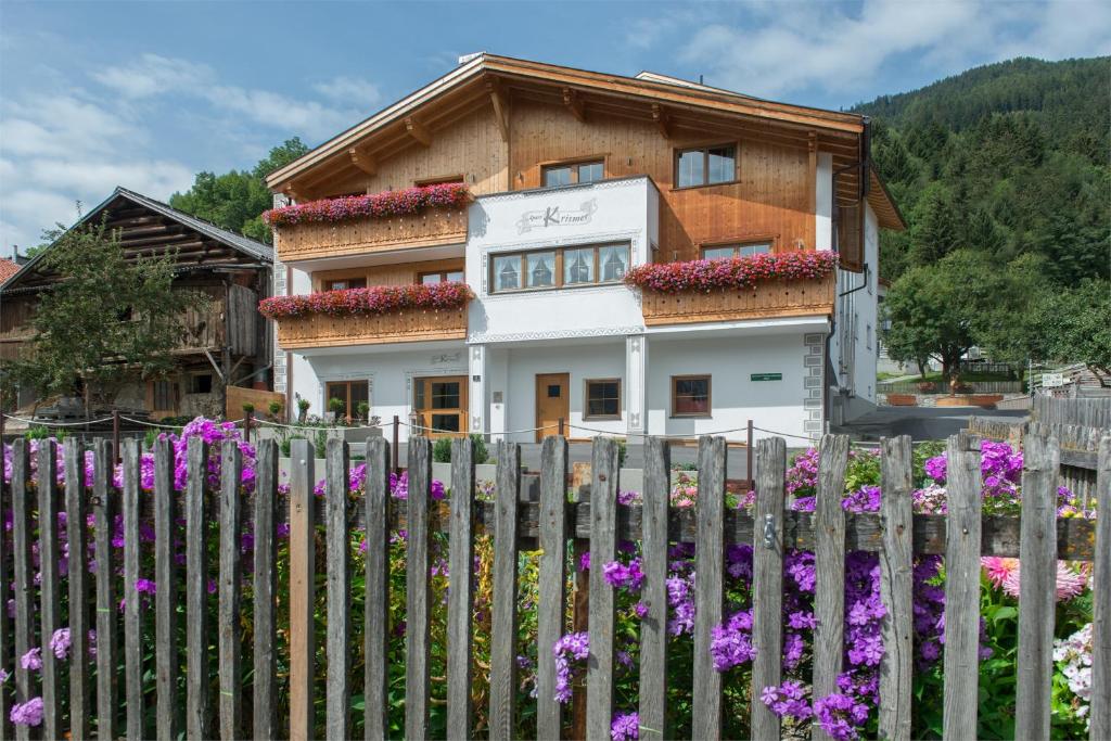 a house behind a fence with purple flowers at Apart Krismer in Ladis
