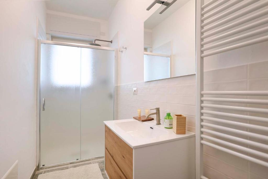La salle de bains blanche est pourvue d'un lavabo et d'une douche. dans l'établissement Lulía bed&breakfast, à Otrante