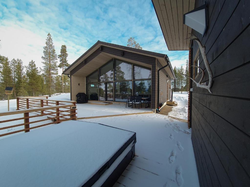 ein Haus im Schnee mit einem Zaun in der Unterkunft Norlight Cottages Ivalo - Tuli in Ivalo
