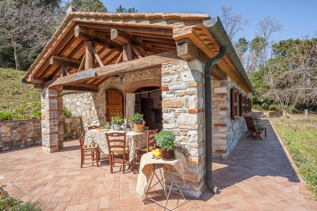 eine Terrasse mit einem Tisch und einem Steingebäude in der Unterkunft Casa nel Bosco in Sassetta