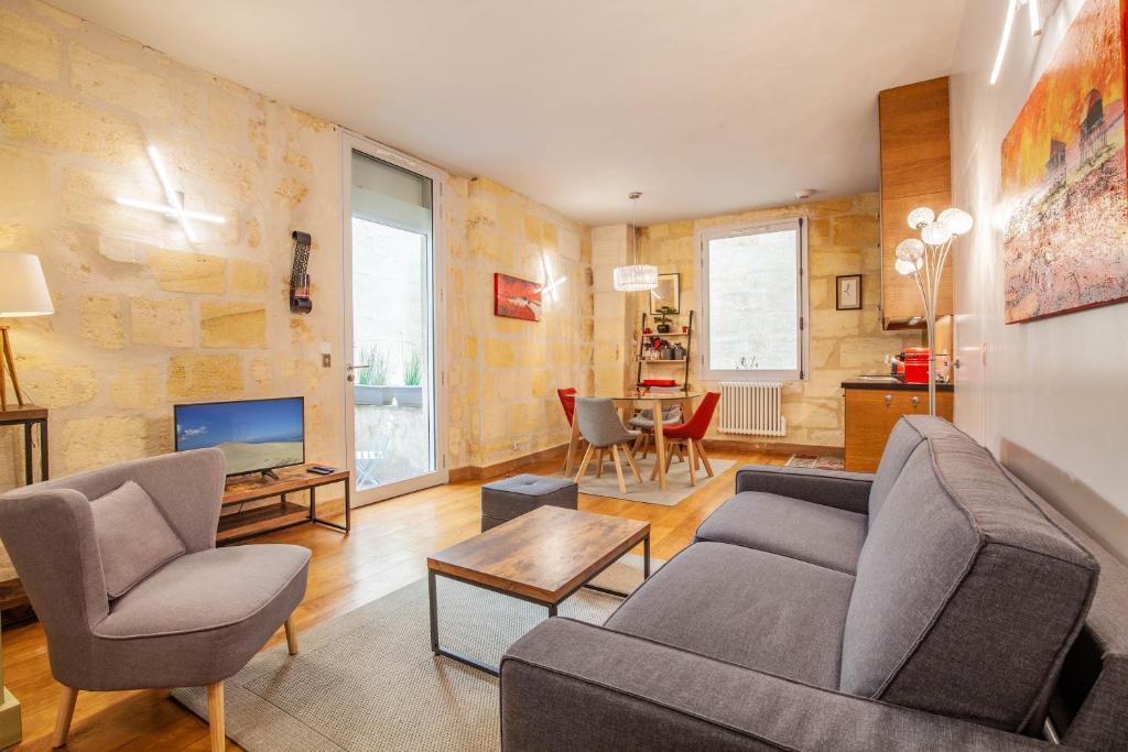 een woonkamer met een bank en stoelen en een tv bij Appart Hypercentre - Le Dijeaux in Bordeaux
