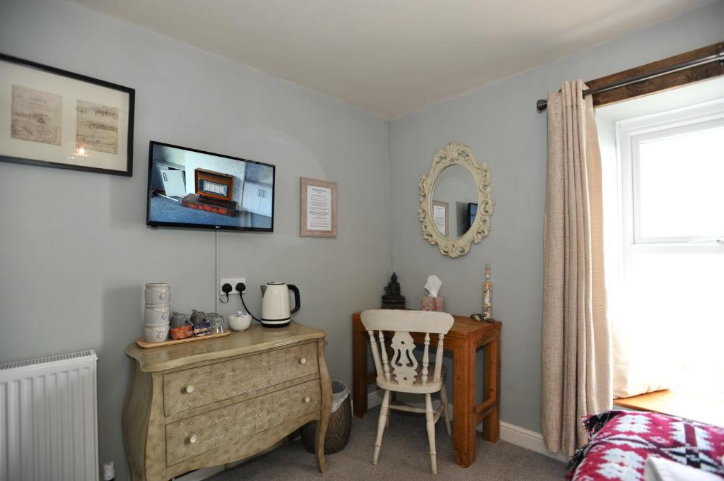 a bedroom with a dresser and a chair and a mirror at Sea View Guest House in Benllech
