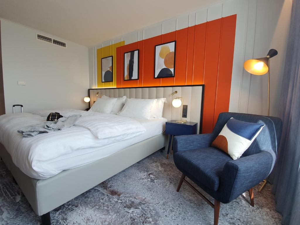 a bedroom with a bed and a chair at voco Dusseldorf Seestern by IHG in Düsseldorf