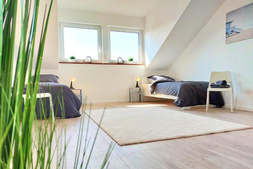 two beds in a attic bedroom with two windows at Holiday Apartments Brachttal in Hellstein