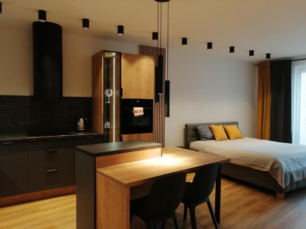a bedroom with a bed and a table and a kitchen at Apartament River House in Szczecin
