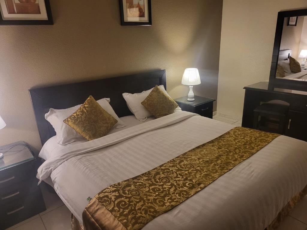 - une chambre avec un grand lit blanc et des oreillers en or dans l'établissement Safwt Aldyar Furnished Units, à Abha