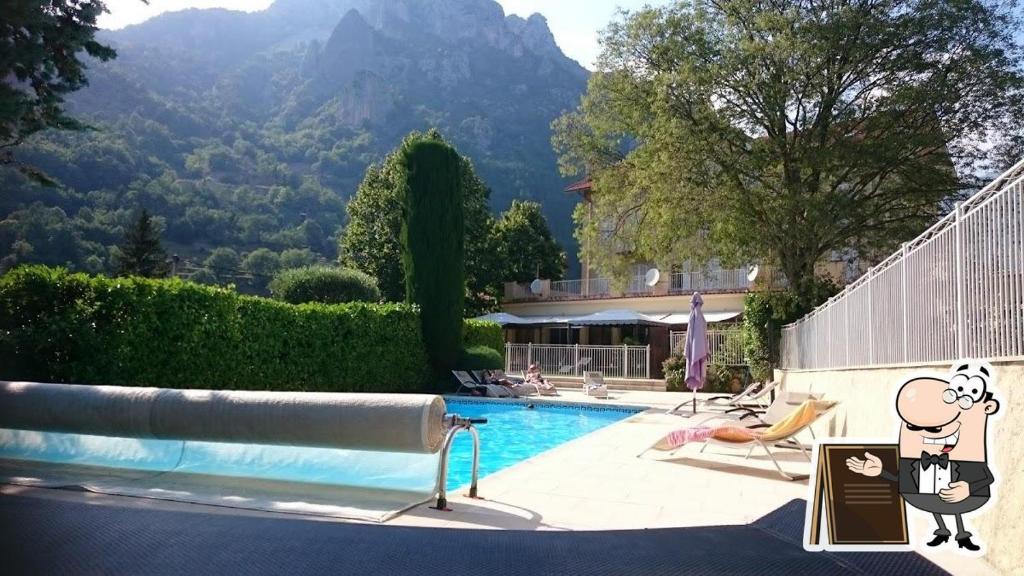 un complejo con una piscina con una montaña en el fondo en HOTEL ST SEBASTIEN en Roquebillière