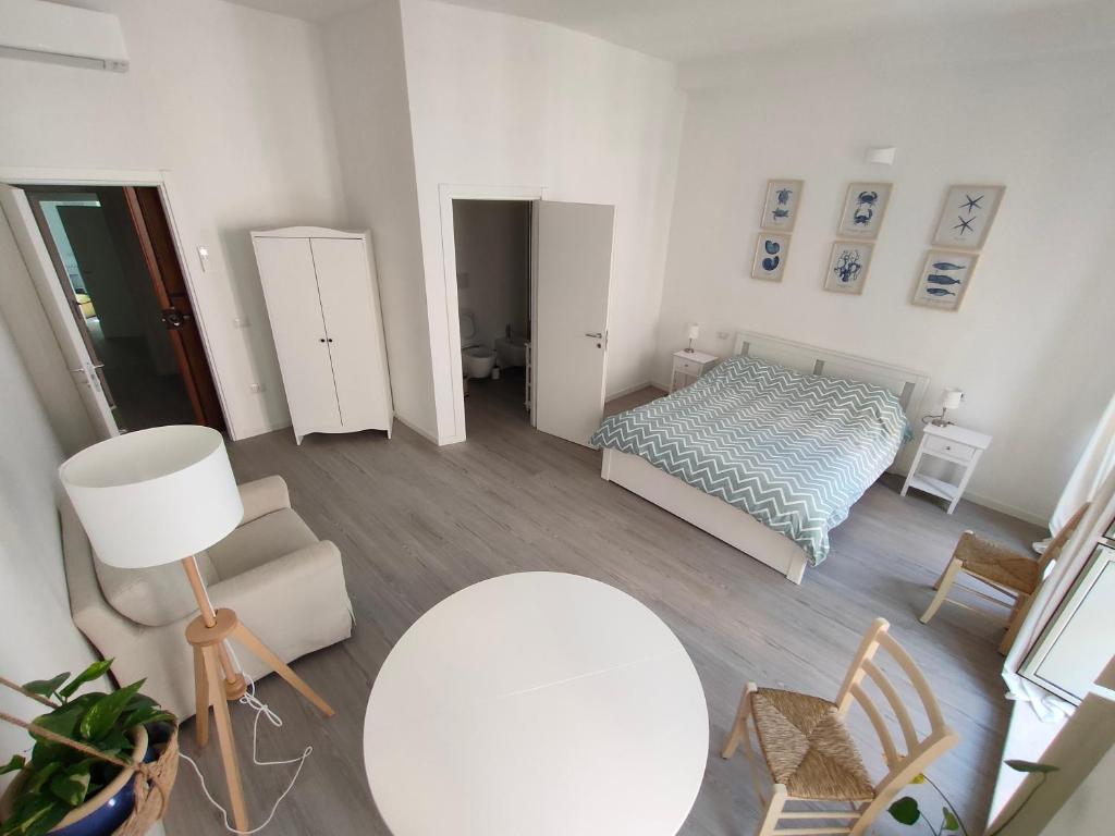 a white room with a bed and a table and a lamp at Casa Marina Guesthouse Cagliari in Cagliari