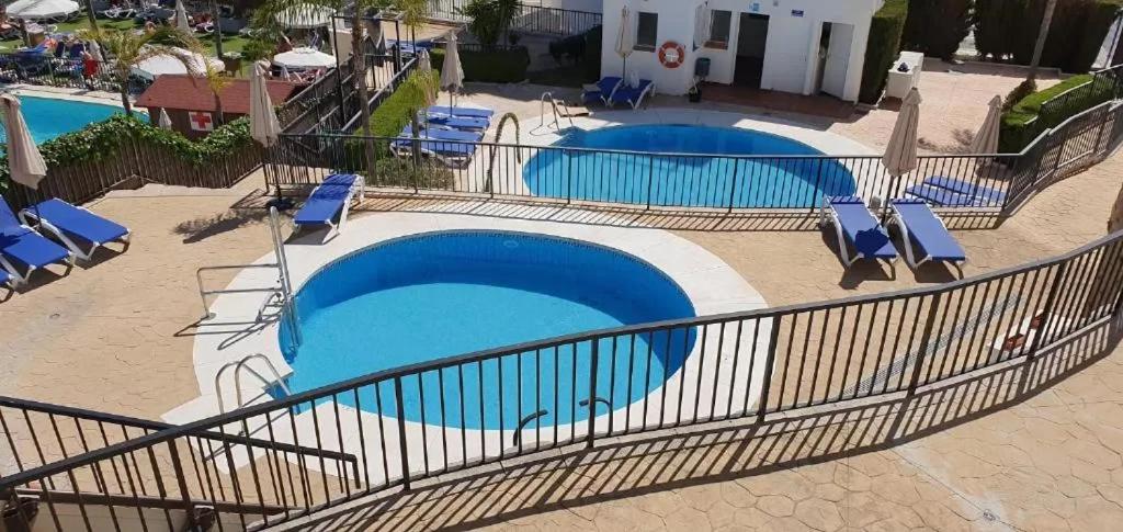 una vista sul soffitto di due piscine con sedie di RESIDENCIAL LOS PATOS PLAYA a Benalmádena