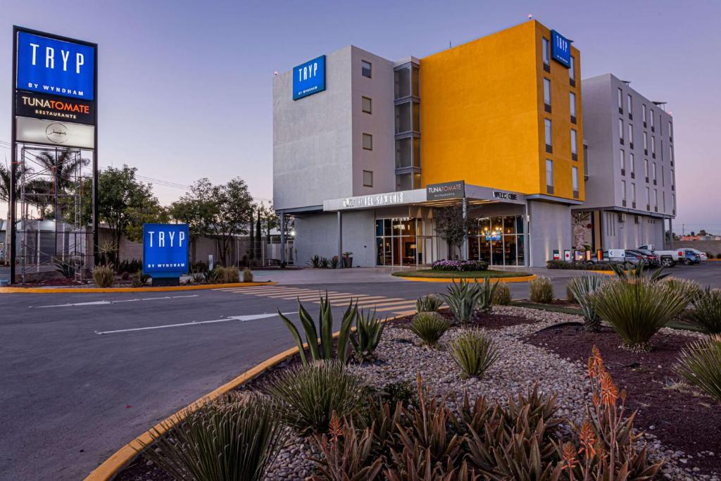 un grand bâtiment avec un parking en face de celui-ci dans l'établissement TRYP by Wyndham San Luis Potosi Hotel & Suites, à San Luis Potosí