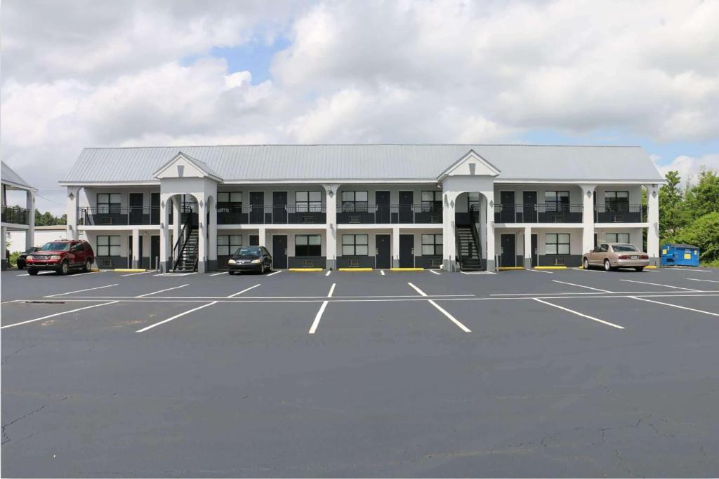 ein großes Gebäude mit Autos auf einem Parkplatz in der Unterkunft Travelodge by Wyndham Calhoun South I-75 in Calhoun