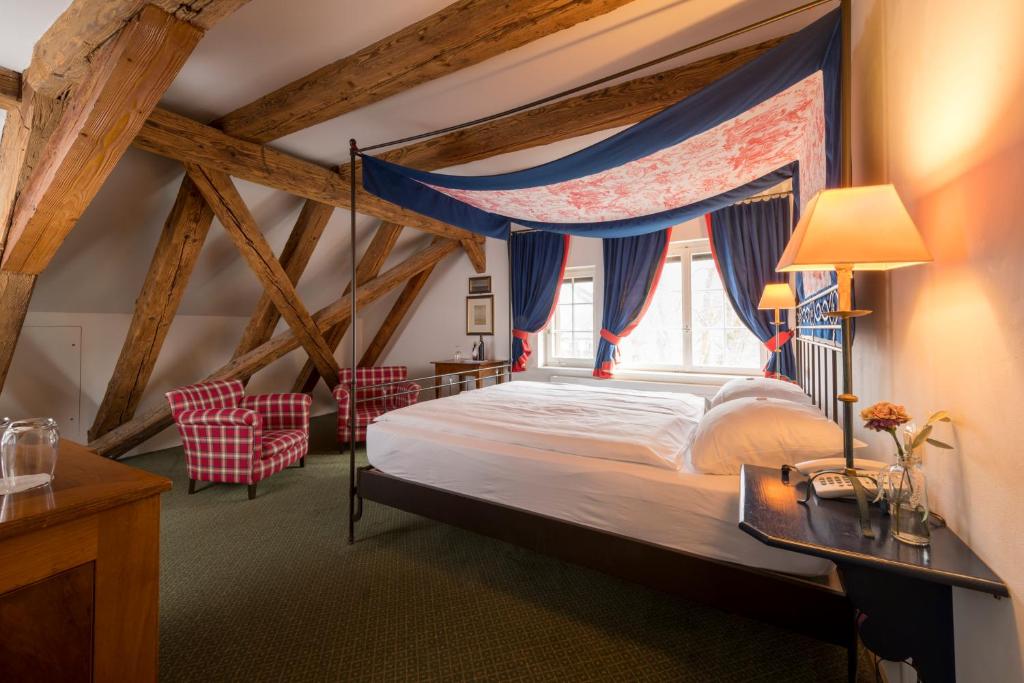 a bedroom with a canopy bed and two chairs at Hotel & Restaurant Alte Rheinmühle in Busingen am Hochrhein