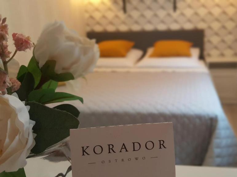 a sign on a table with two beds and flowers at Korador in Ostrowo
