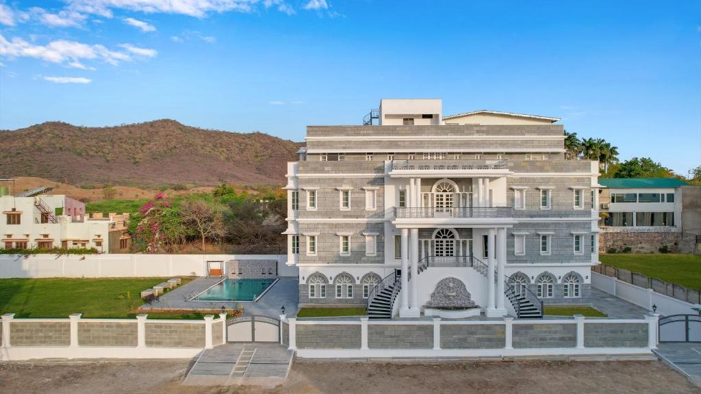 a large white house with a pool in front of it at Boheda Manor - Luxury Retreat in Udaipur