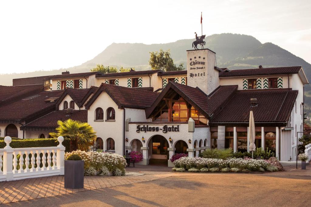 ein großes weißes Gebäude mit einem Berg im Hintergrund in der Unterkunft Swiss-Chalet Merlischachen - Romantik Schloss-Hotel am See in Küssnacht