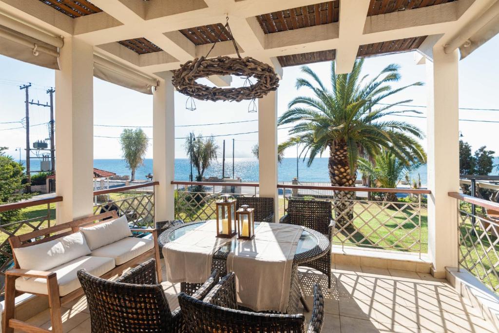 a patio with a table and chairs and the ocean at #FLH - Vitamin Sea Beachfront Villa, Sithonia in Metamorfosi