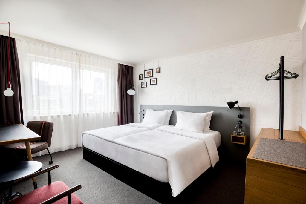 pentahotel Brussels City Centre في بروكسل: غرفة في الفندق مع سرير أبيض كبير ومكتب