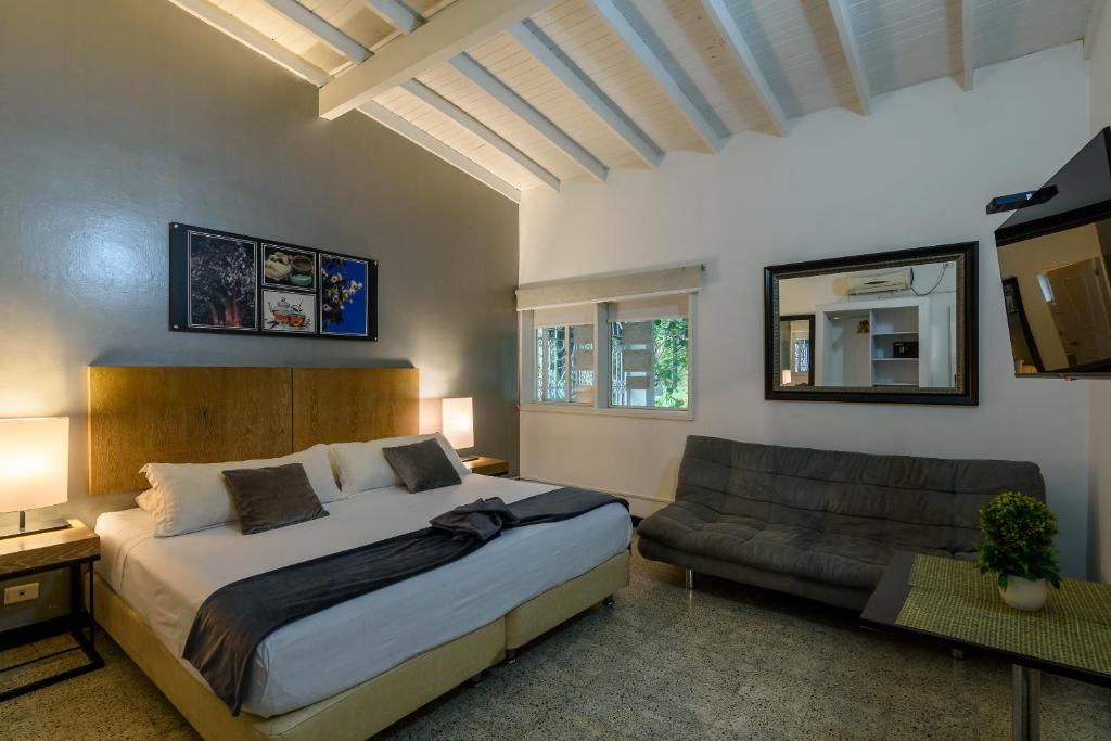 - une chambre avec un grand lit et un canapé dans l'établissement Hotel Aromax del Campestre, à Medellín