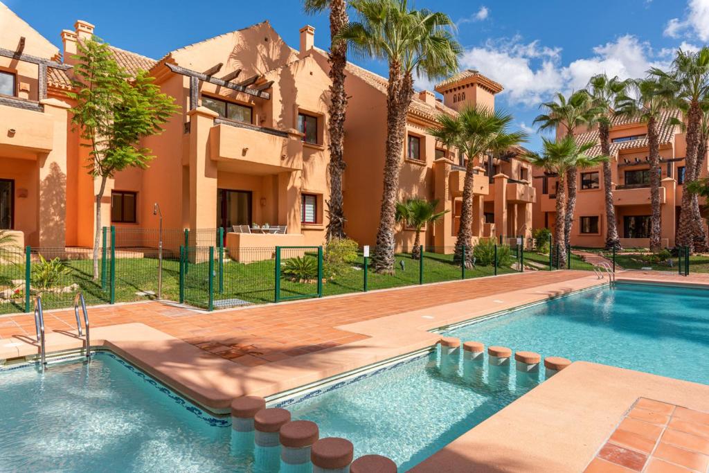 a villa with a swimming pool and palm trees at Ipanema Paradise - Apartamento de dos dormitorios en el Mar Menor in Los Alcázares